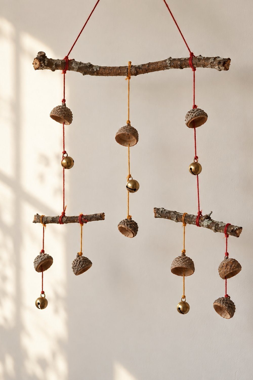 Bricolages d’automne avec des matériaux naturels Mobile artisanal de cupules et clochettes suspendues à des branches par des fils
